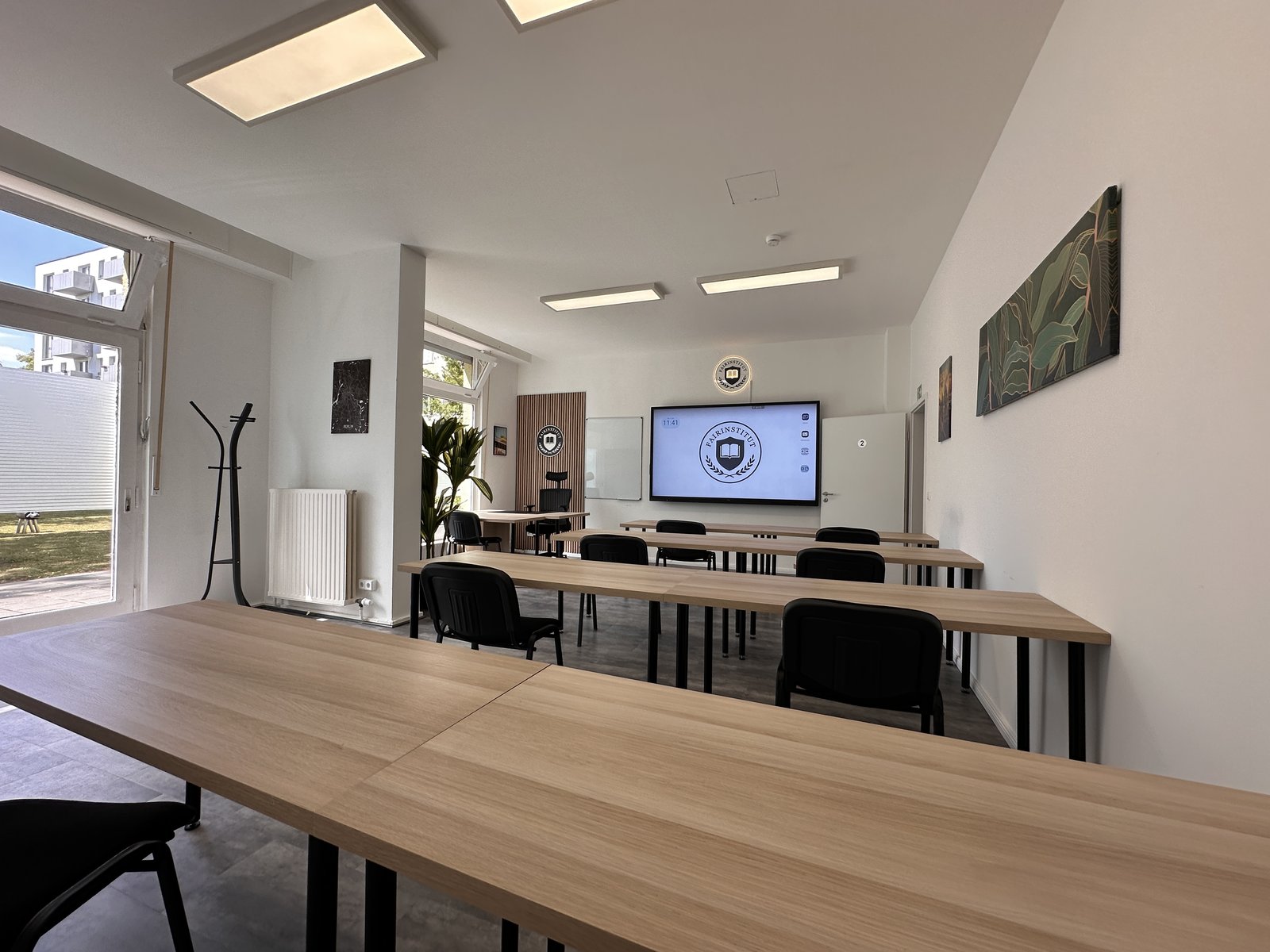 Tischreihen und Smartboard im Klassenraum des fairInstitut